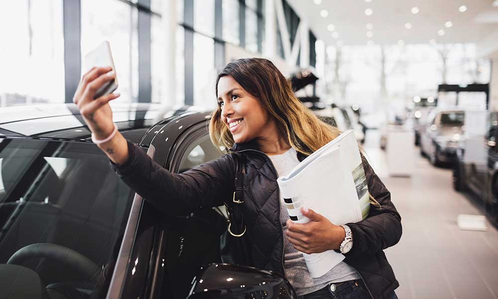 woman taking selfie by new car