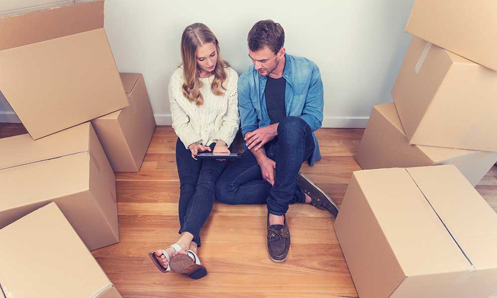 couple sitting in a new home with unopened boxes
