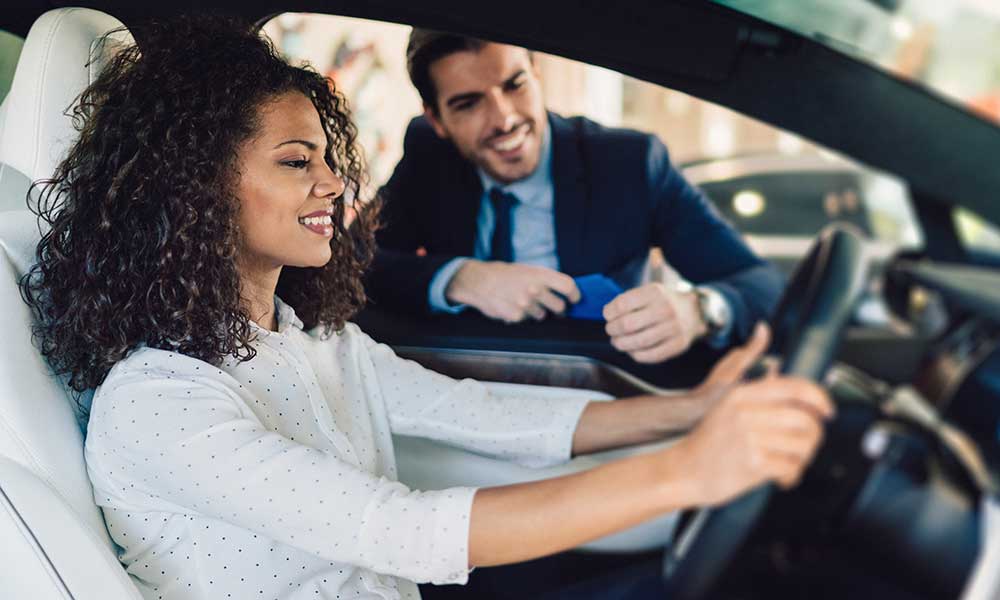 woman smiling behind the wheel of a new car