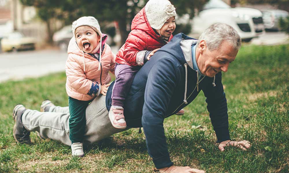 grandfather playing with his granddaughters outside