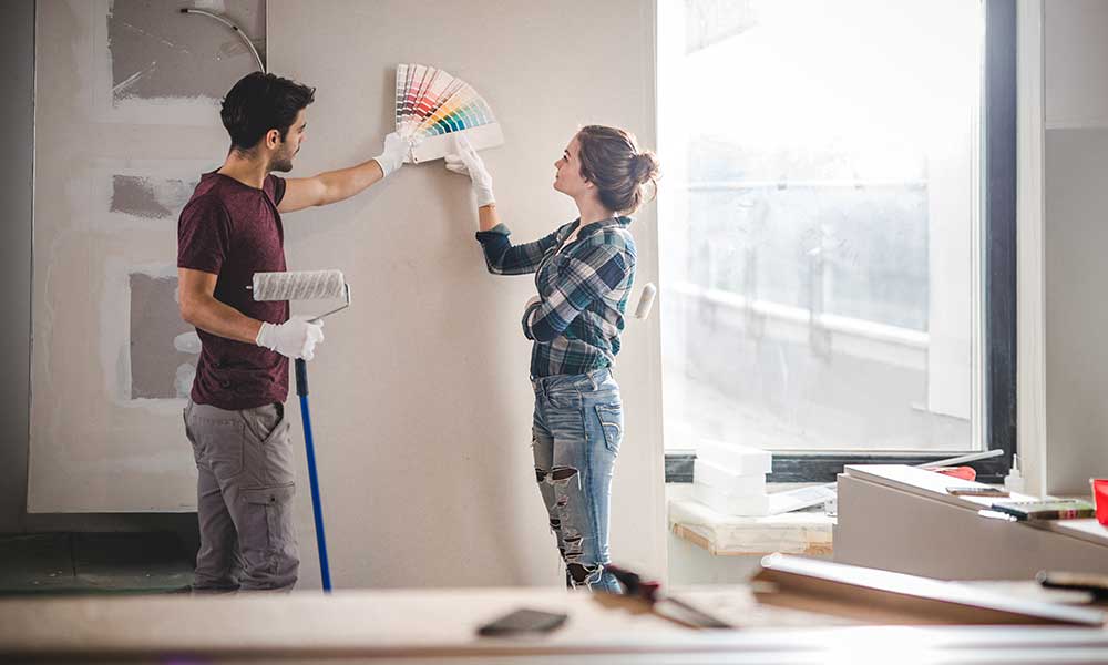 couple talking through paint color swatch options for wall