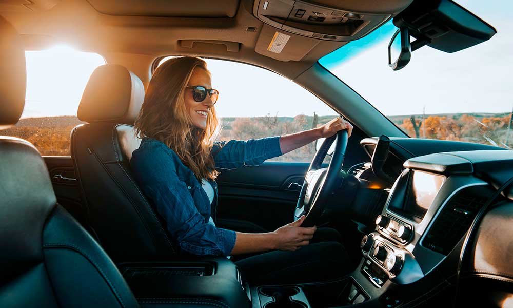woman in sunglasses smiling while driving in car