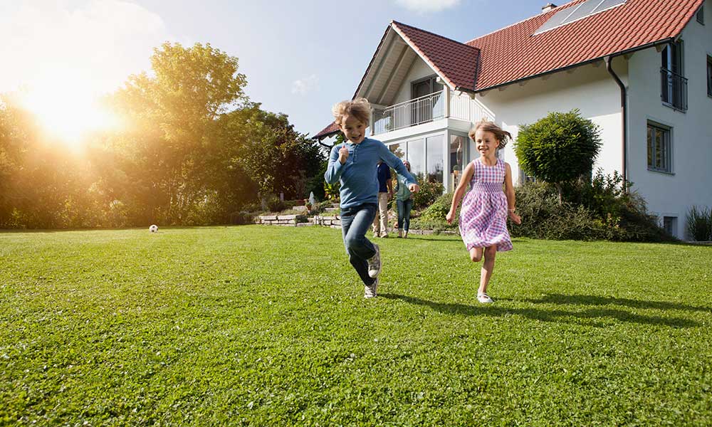 brother and sister running in the yard by their house