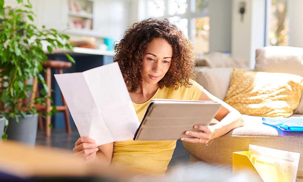 woman reviewing her finances on tablet from home