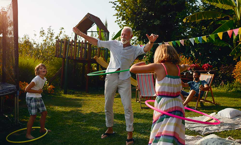 Multi generation family hula hooping in backyard