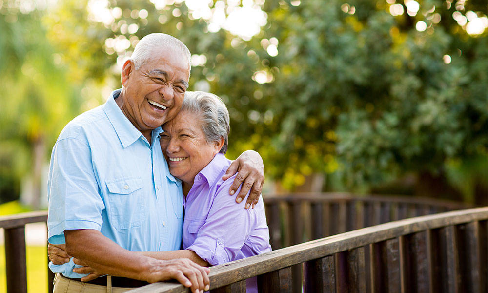 A charming elderly couple laughing together on bridge.