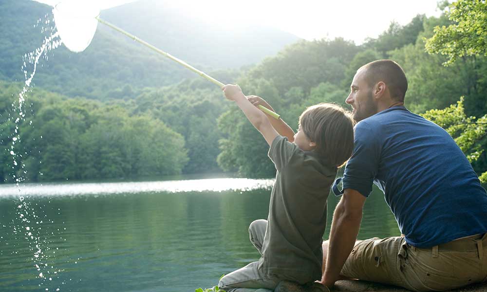 Father and son fishing with boy holding up fishing net