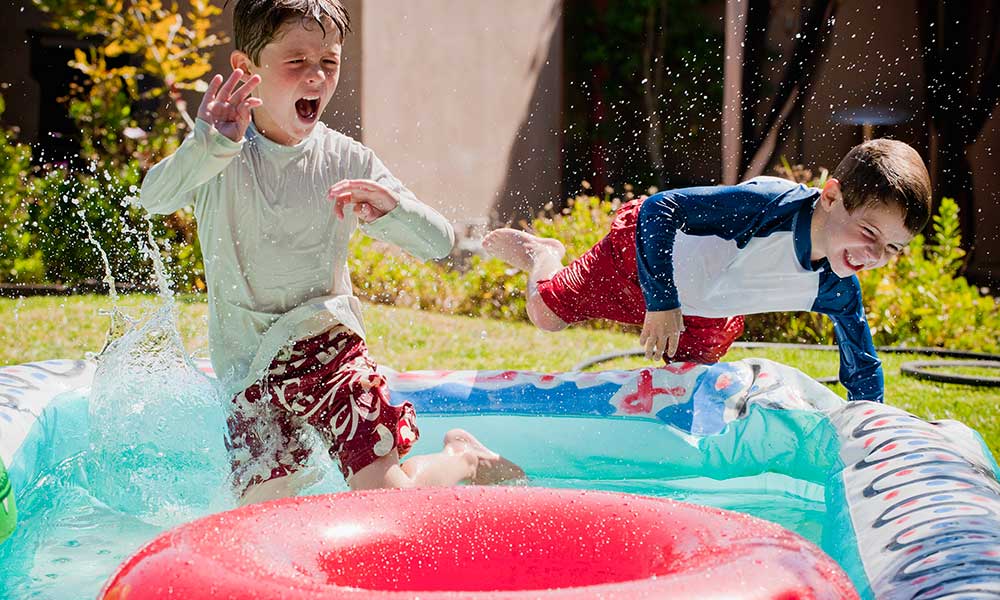 excited boys leaping into backyard inflatable pool