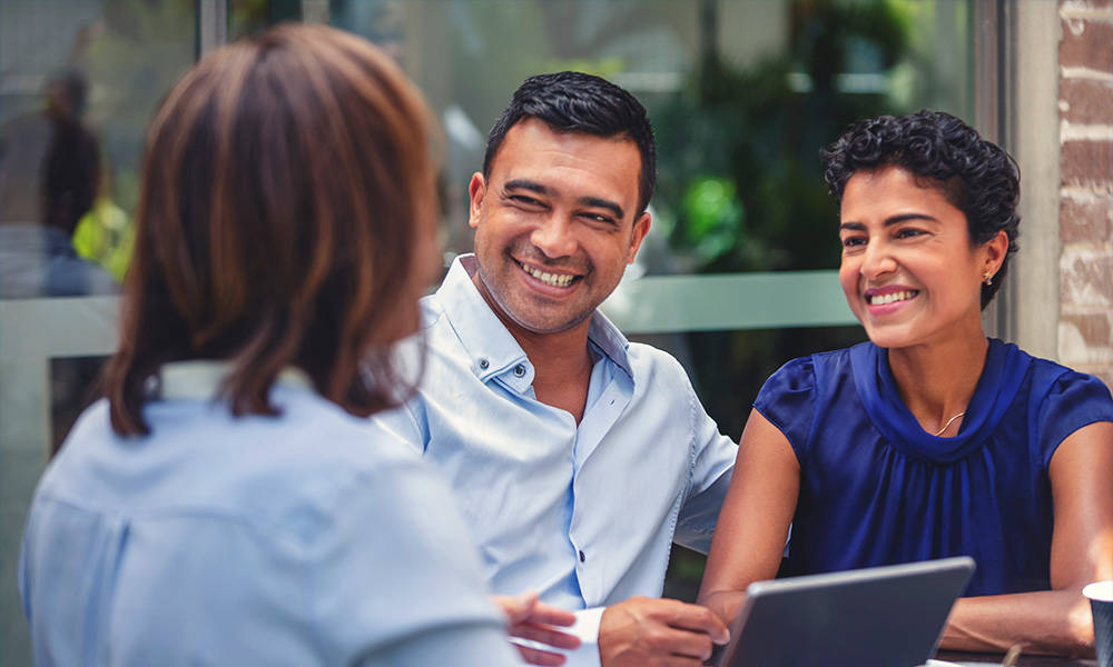 Happy couple meeting with their CommunityAmerica Wealth Advisor. They are looking at a laptop computer or digital tablet.