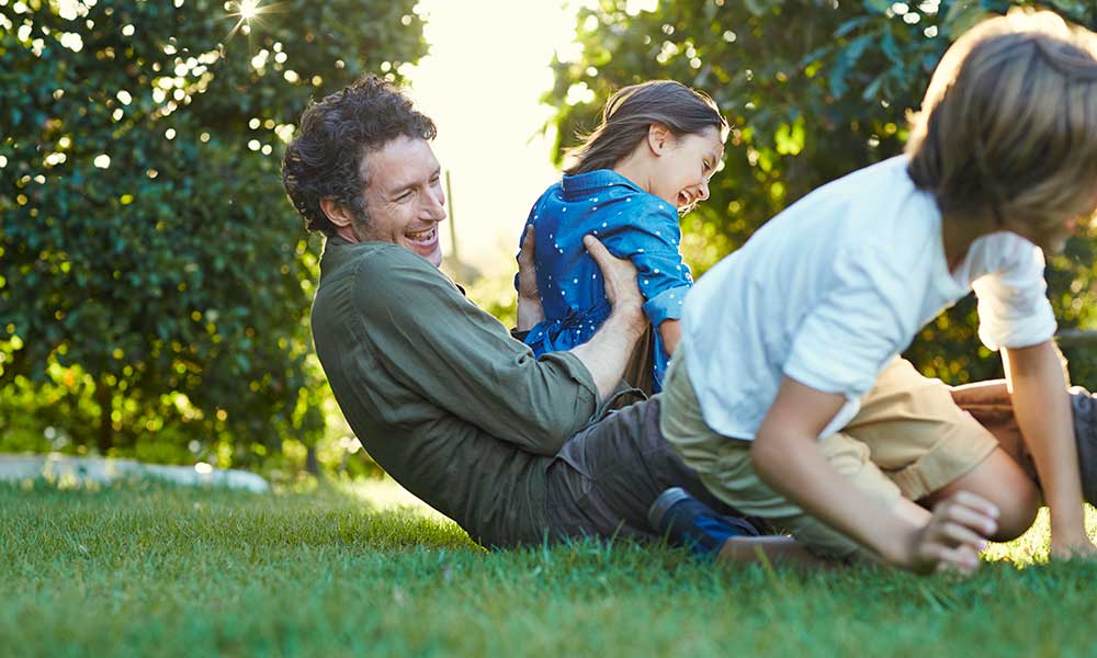 father playing in backyard with son and daughter