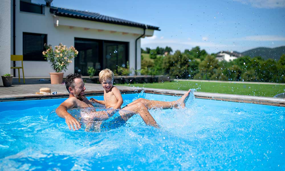 Father with small son playing in swimming pool in backyard