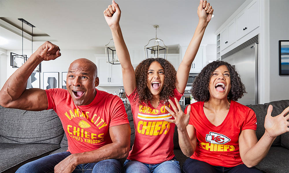 three football fans cheering on the kansas city chiefs