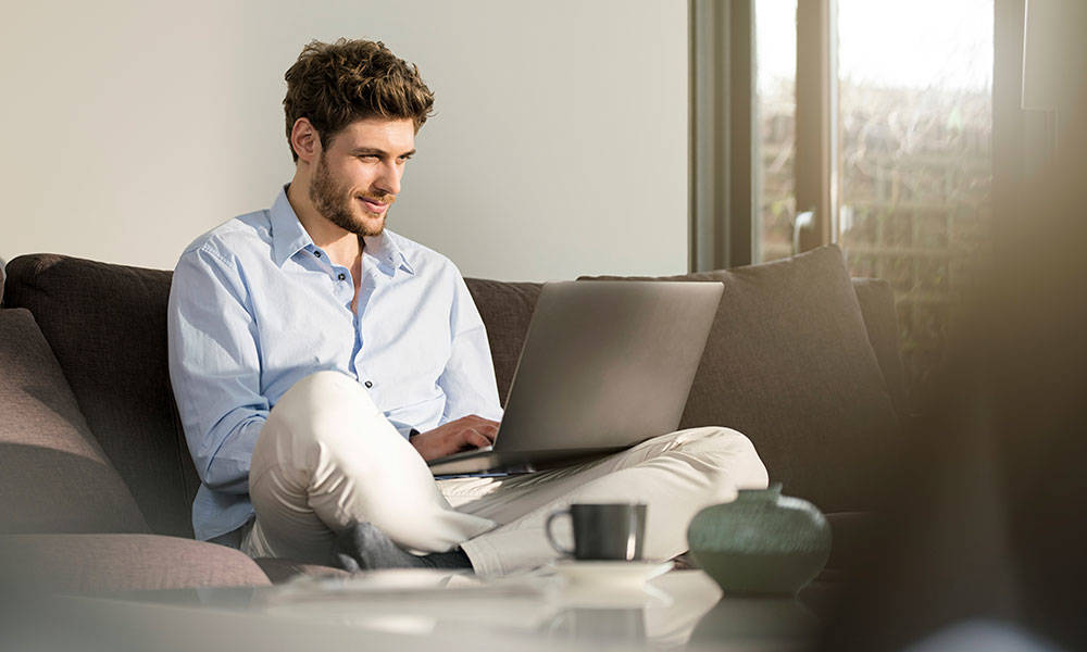 man going through his finances at home on a laptop
