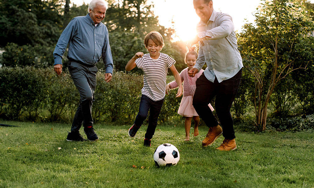 multigenerational family playing soccer in backyard