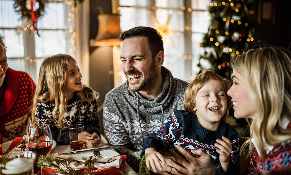 family enjoying meal at dinner table with christmas tree in background