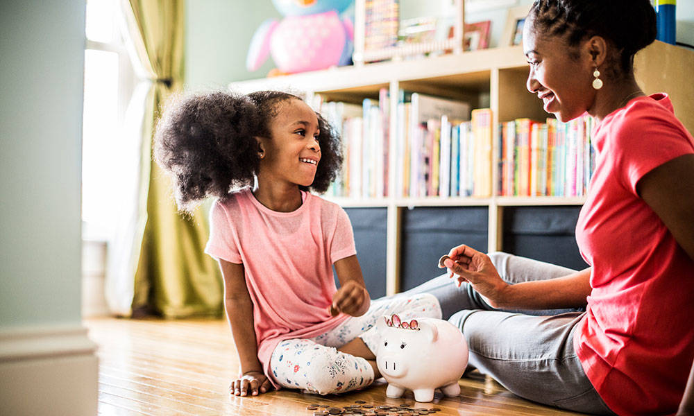 mother and daughter putting money in piggybank