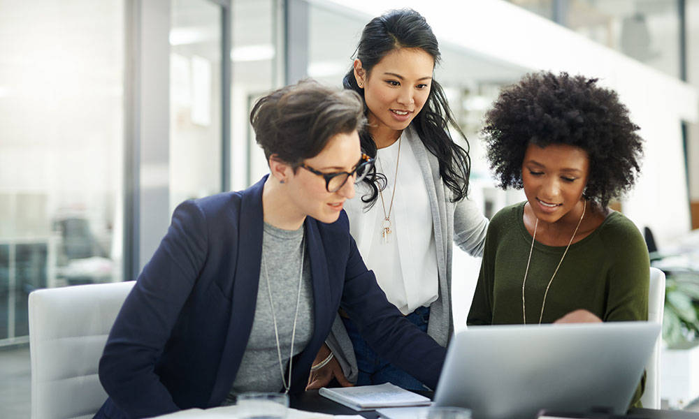 group of businesswomen using a laptop during a meeting at work