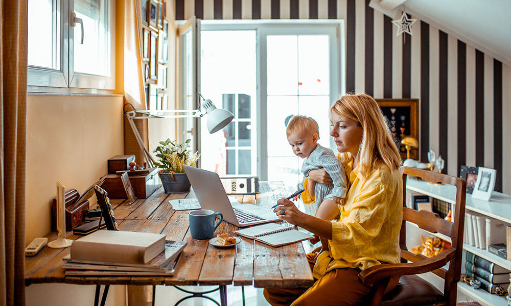 woman looking at finances on computer with toddler son in lap