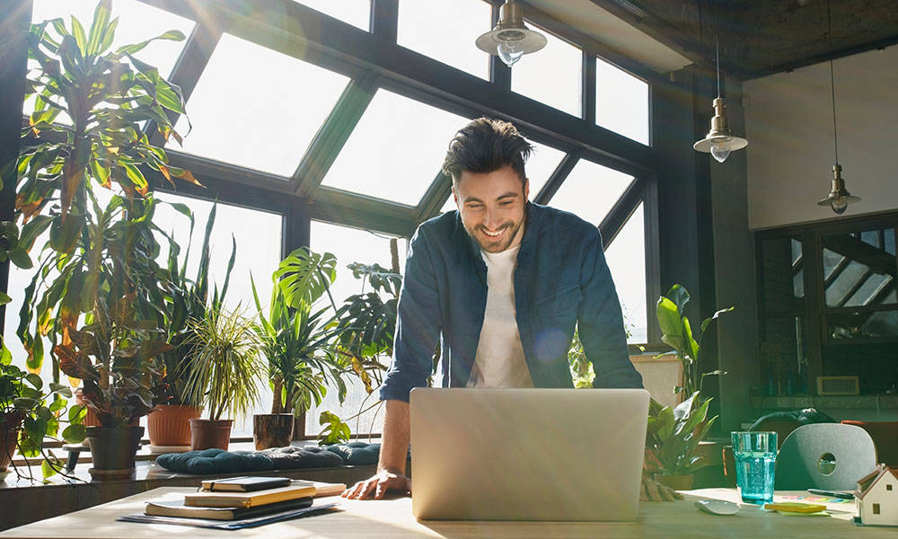 business person smiling while working from his own business on laptop
