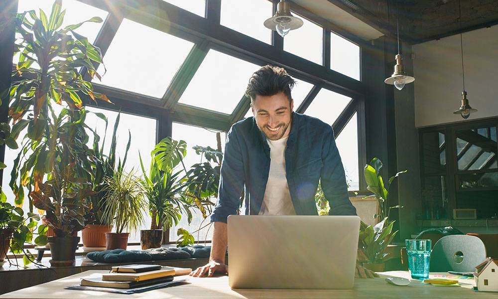 business person smiling while working from his own business on laptop