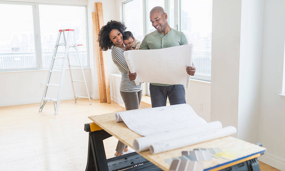 family of 3 with newborn son looking at blueprints in home