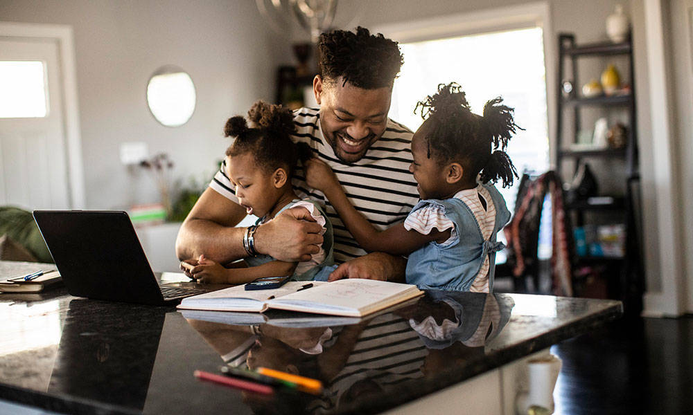 father working from home playing with daughters