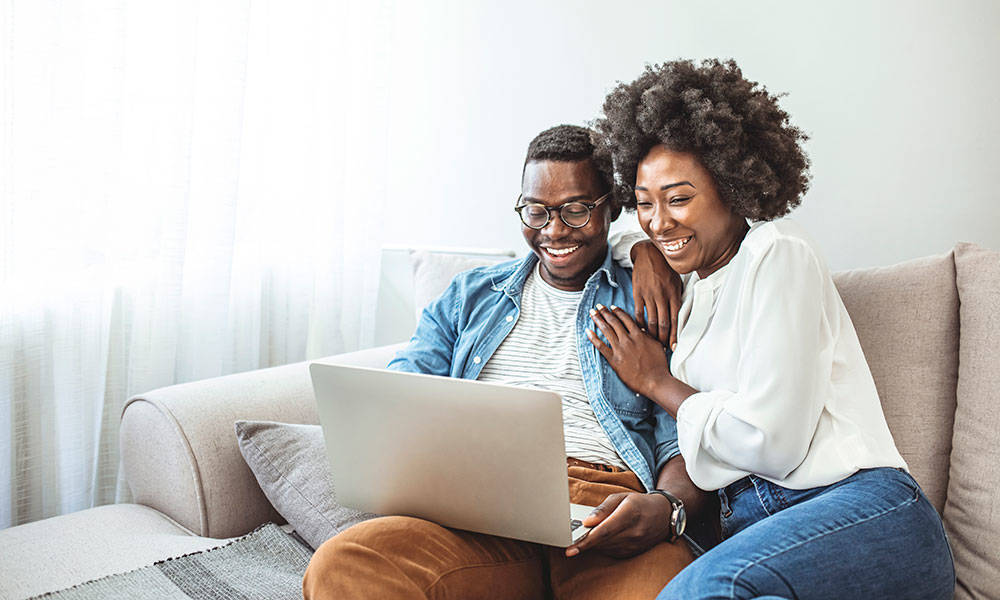 happy couple reviewing finances on laptop
