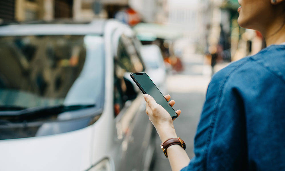 woman looking at smartphone and waiting for car ride