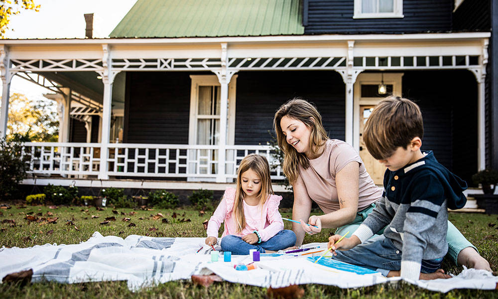 mother with two children playing outside with arts and crafts