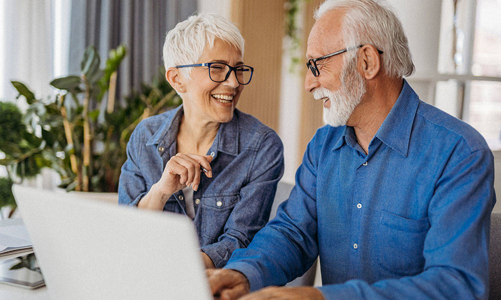 senior couple working together at home on laptop