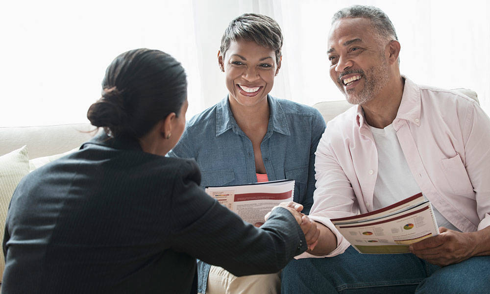 senior couple talking to businesswoman about finances