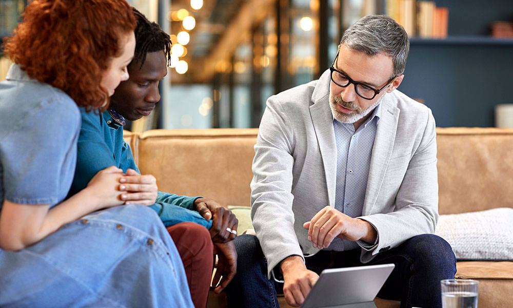 financial advisor pointing out something on tablet to couple