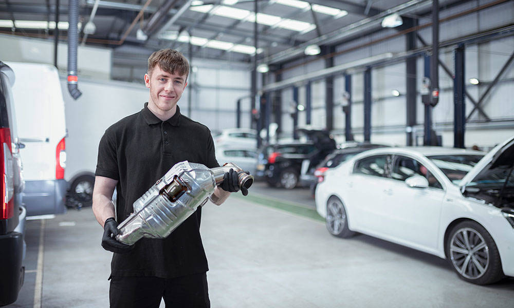 engineer holding catalytic converter in car service center