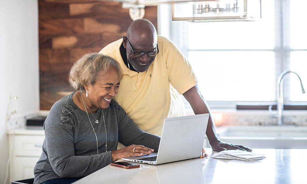 senior couple looking at information on laptop in kitchen