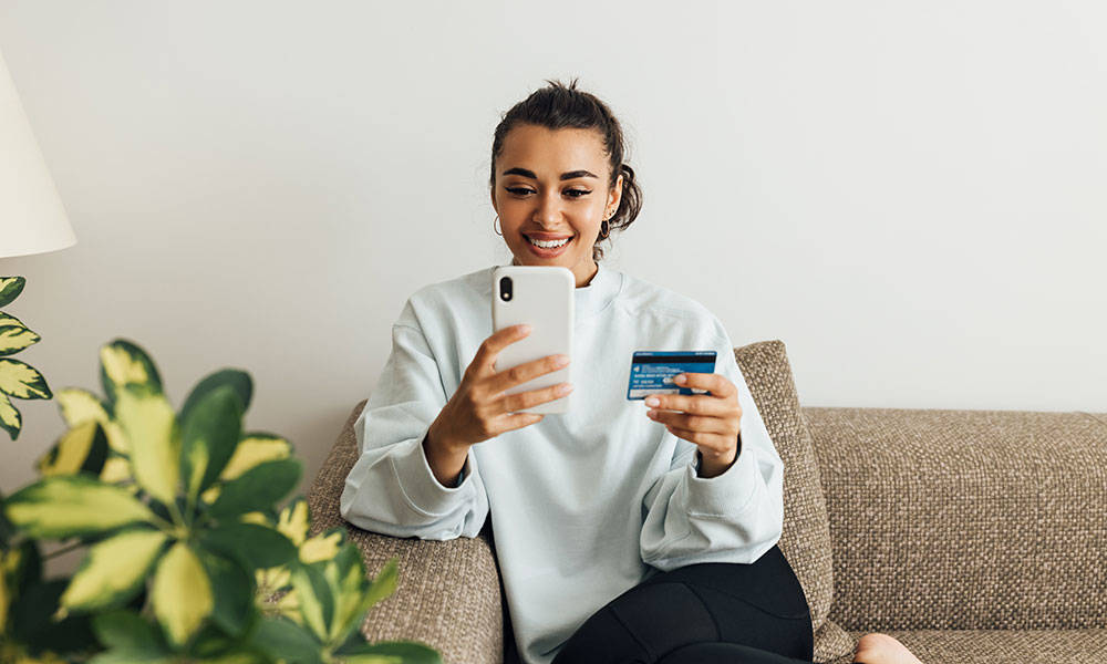 woman making a purchase on smartphone and looking at credit card