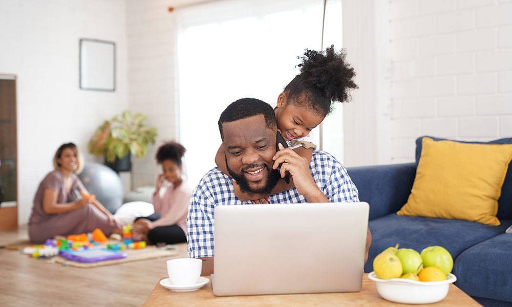 kid teasing father while working on a laptop