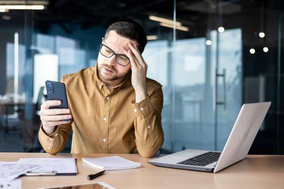 Man looking at fraudulent text scam on his phone in the office.