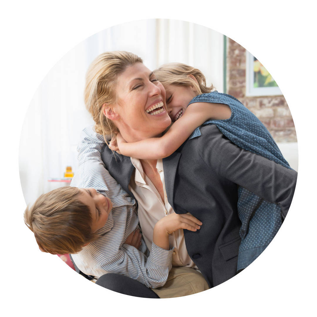 Two young kids playfully greeting their mother who has just returned from work.