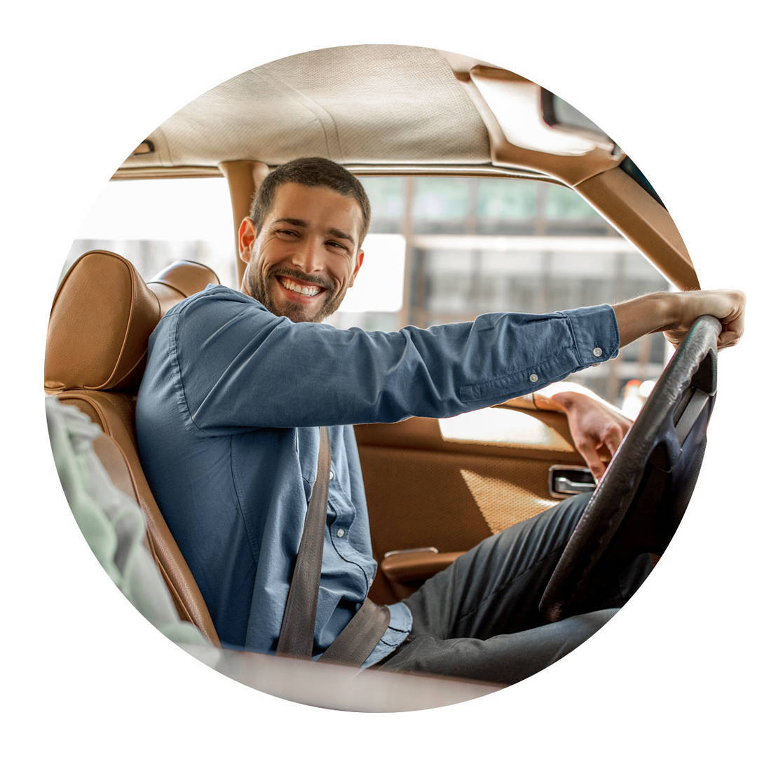 Young man smiling as he takes his new car out for a drive.