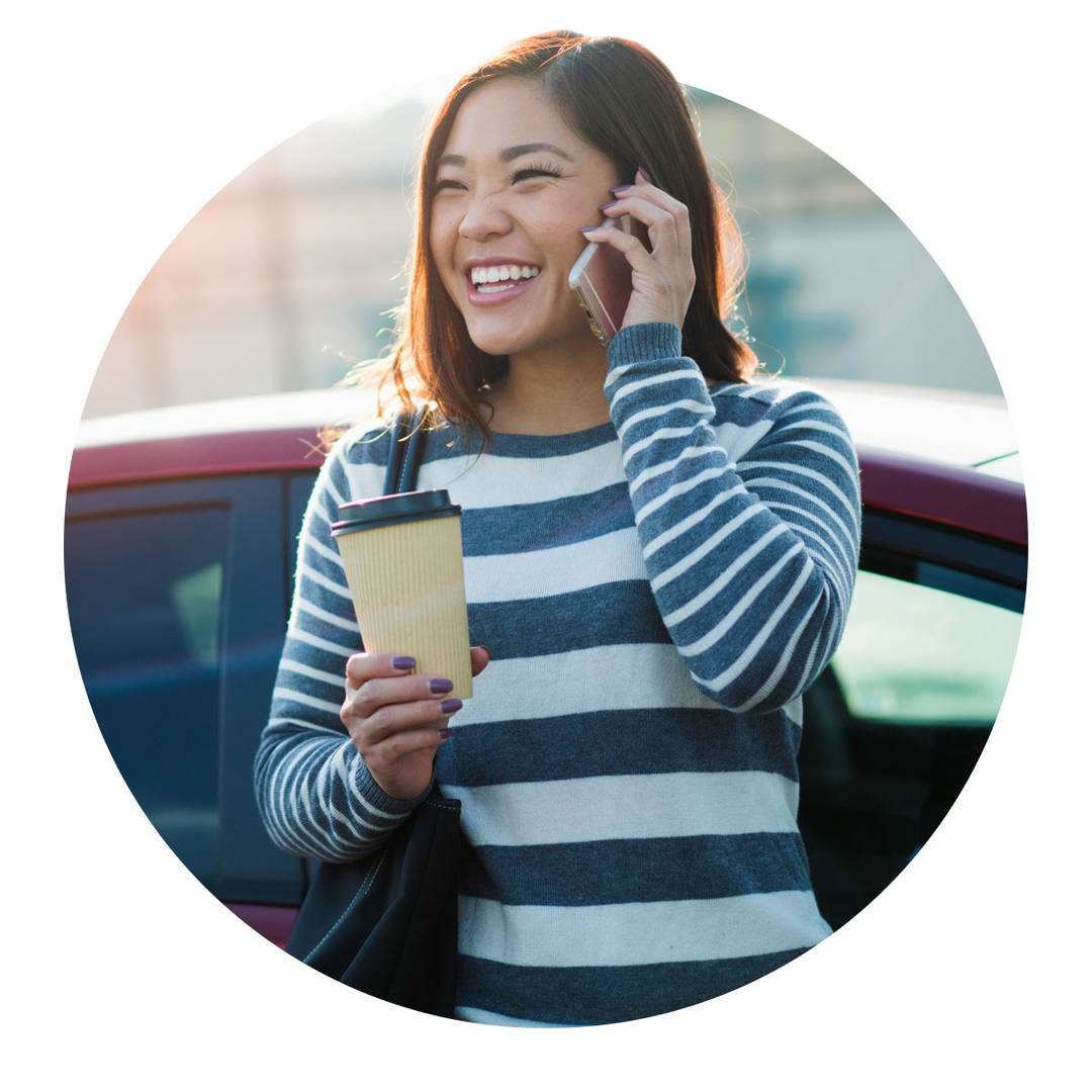 Young woman talking on the phone and holding a coffee cup.