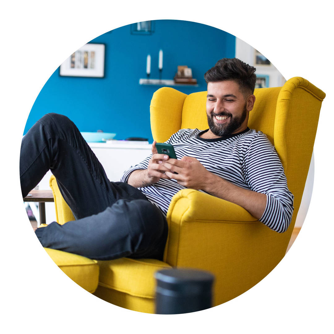 A man sitting in a yellow chair, on their cell phone.
