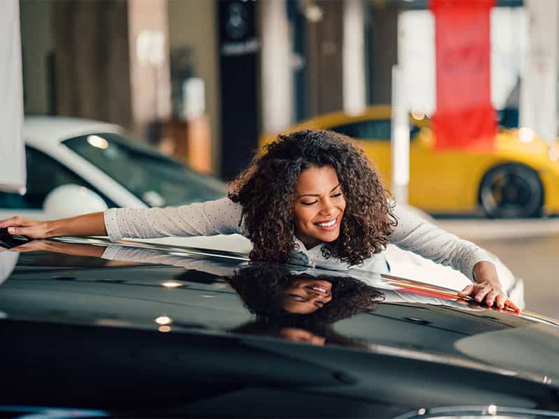 Young woman in love with her new car and giving it a big hug.