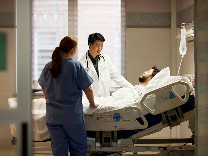 Doctor and nurse talking to patient in hospital bed.