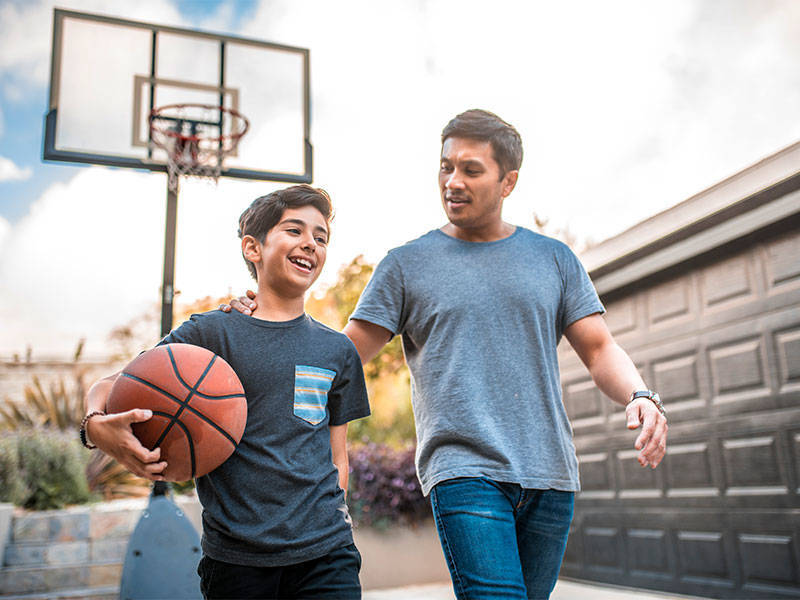 Happy boy after the basketball match with his father in the driveway.