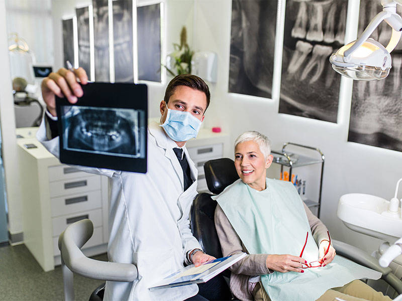 Male dentist going over dental x-ray image with patient.