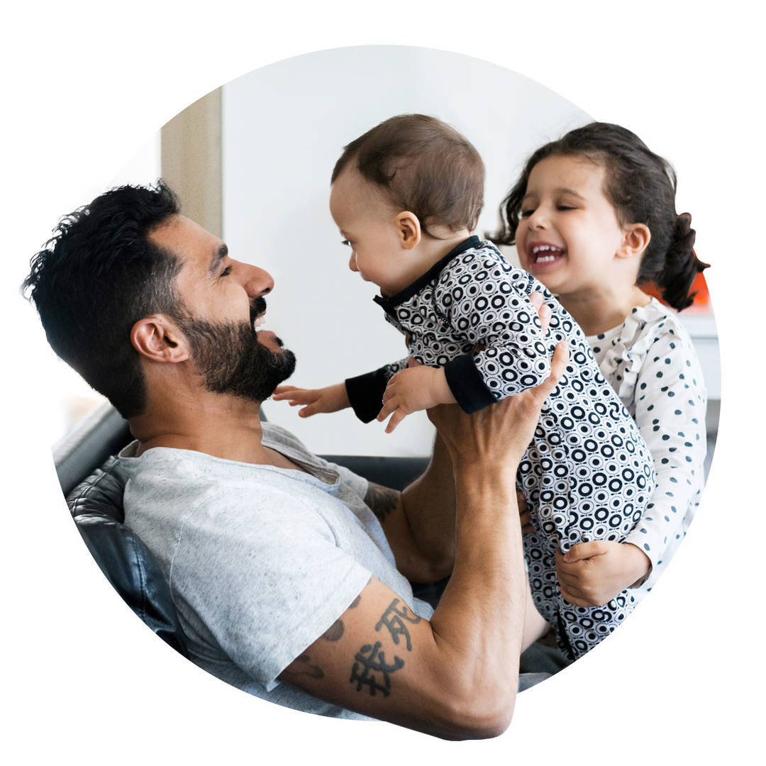Young father and daughter playing with baby girl on sofa at home.