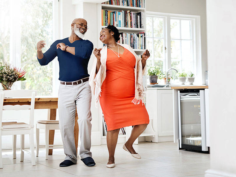 Happy mature couple dancing together at home.