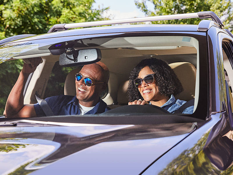 Mature couple happily driving their SUV through the neighborhood.