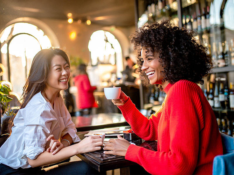 Two smiling female friends having a coffee at a cafe.