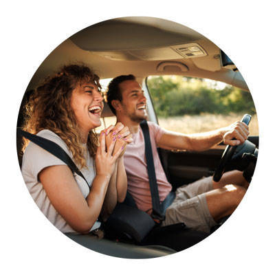 Smiling couple laughing in car with windows down.